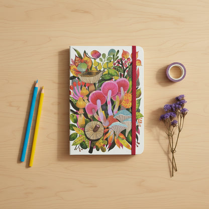 Notebook with colorful mushroom design on a desk top with color pencils, washi tape and some dried flowers