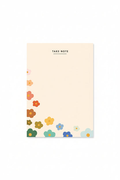 Notebook with floral design on cover surrounded by pink and white flowers on a beige background
