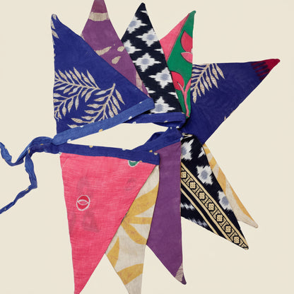 Colorful and recycled fabric triangle garland arranged in a decorative pattern on a white background