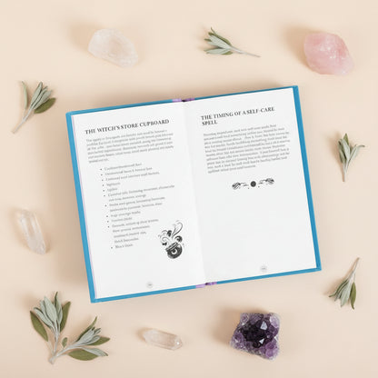 Open book with text and symbols on a white surface with candles and dried lavender.
