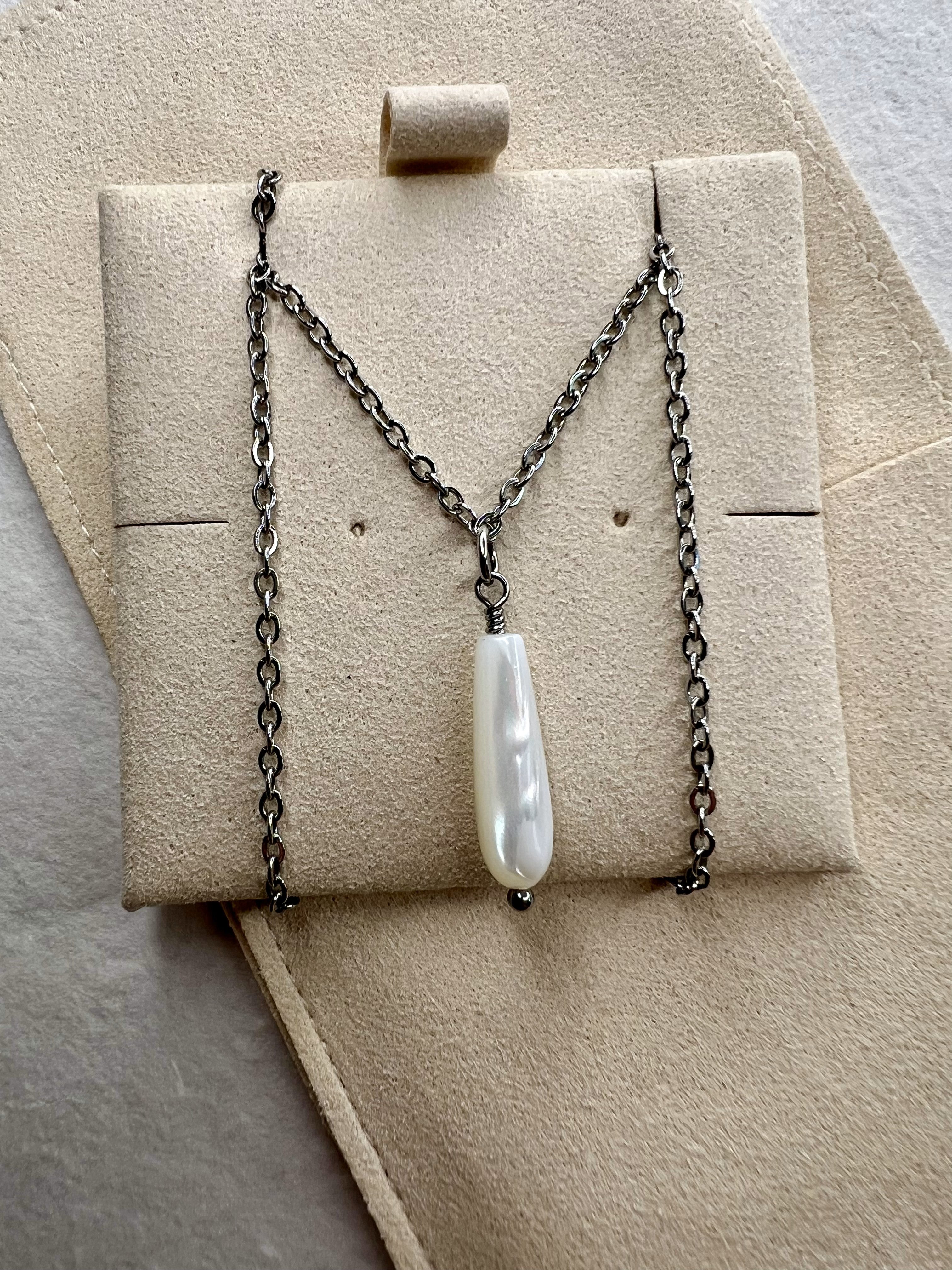 Silver Mother of Pearl drop necklace on soft fabric background