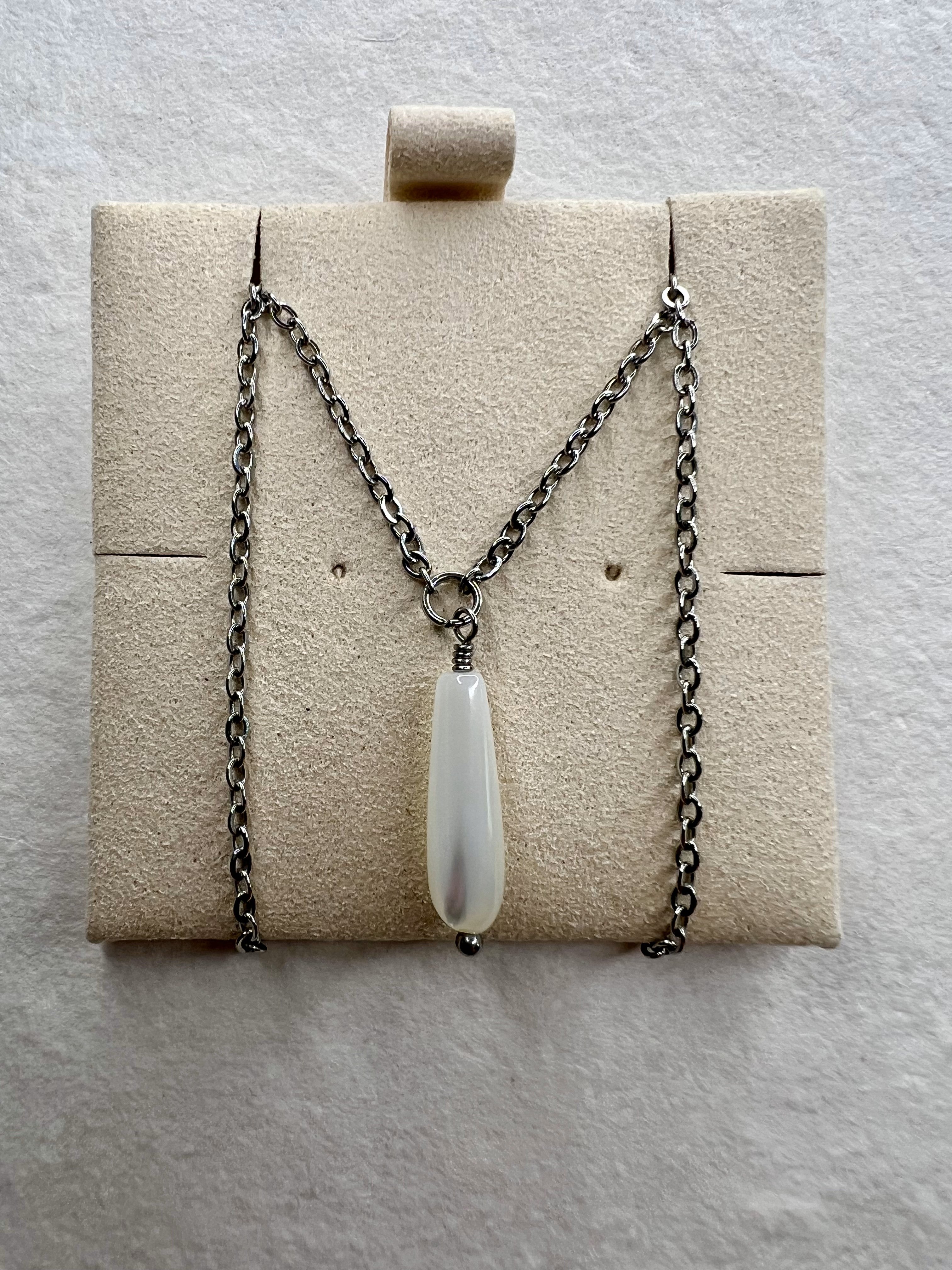 Close-up of iridescent teardrop pendant and silver chain