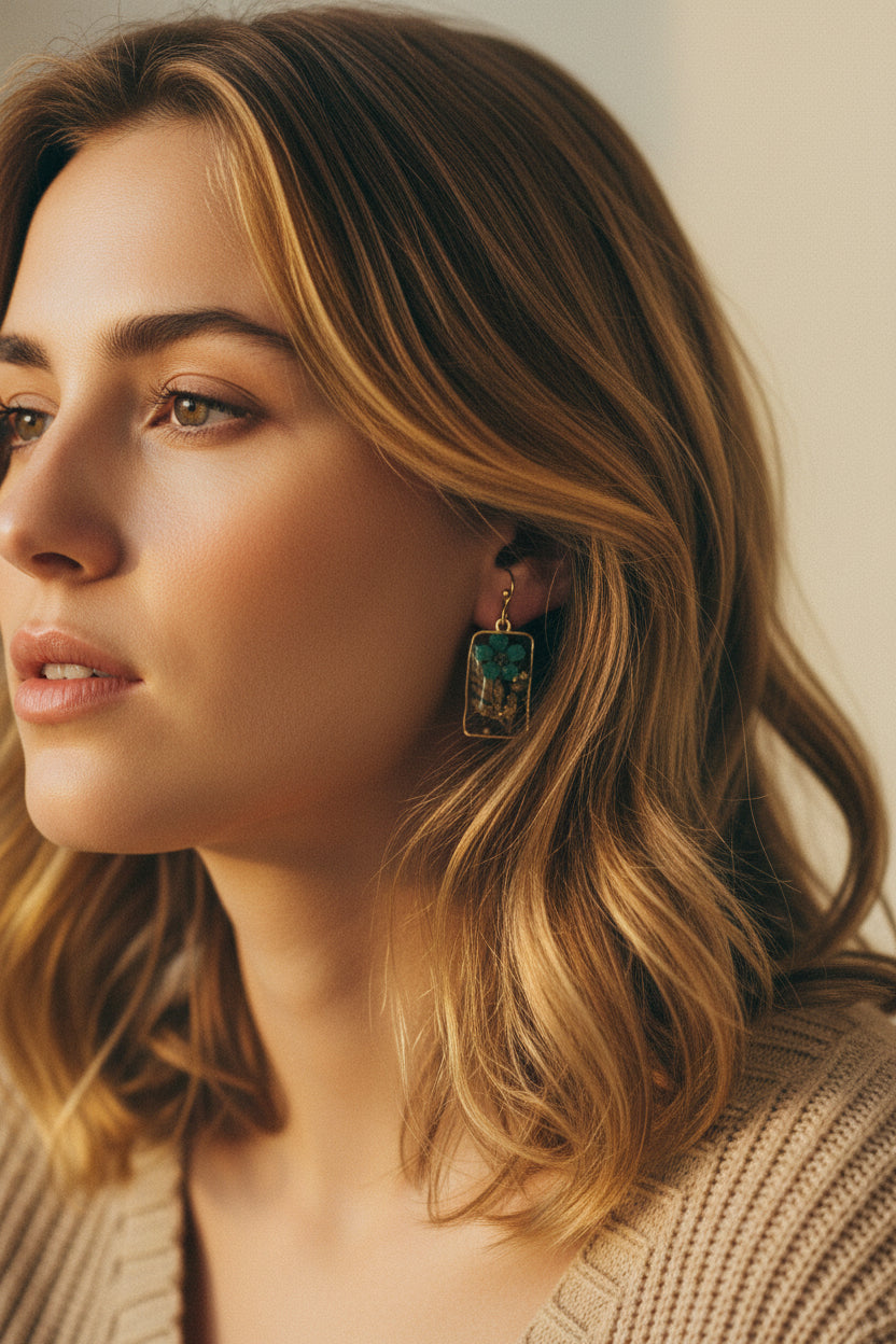 Close-up of a woman wearing earrings  from Rochambeau Home with pressed flowers and a neutral background