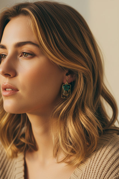 Close-up of a woman wearing earrings  from Rochambeau Home with pressed flowers and a neutral background