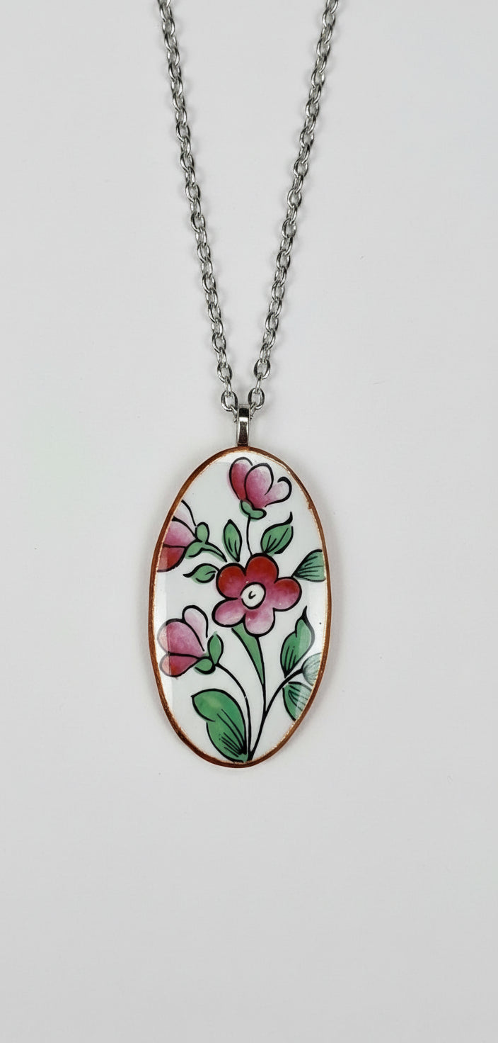 Necklace with an oval pendant featuring pink and green floral design on a plain background