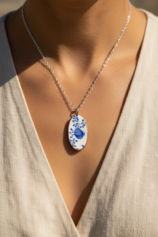 Necklace with an oval pendant featuring blue floral design on a beige background