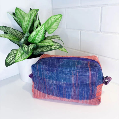 Blue and red checkered pouch on a white surface with a plant in the background