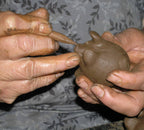Hands working with clay on a textured fabric background