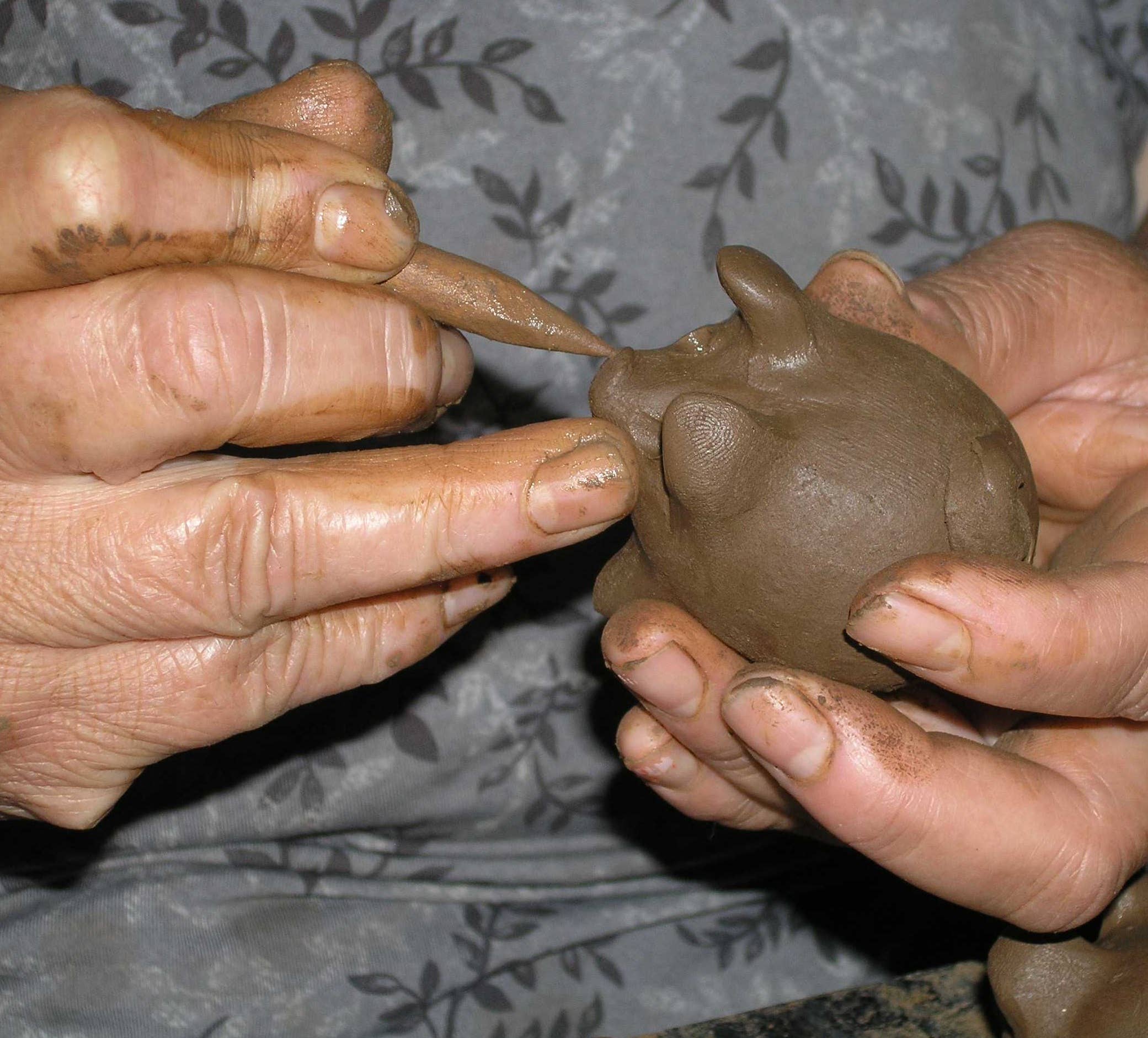 Hands working with clay on a textured fabric background