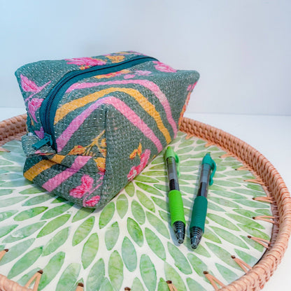 Colorful fabric zippered box pouch with floral patterns on a woven tray with green leaf pattern