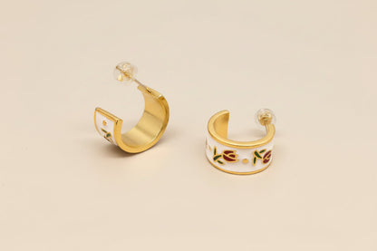 Gold hoop earrings with colorful designs on a gray background