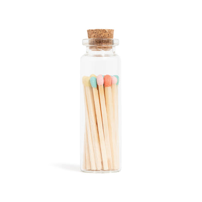 Pastel-colored matchsticks in a corked glass vial with an adhesive match striker at the bottom.