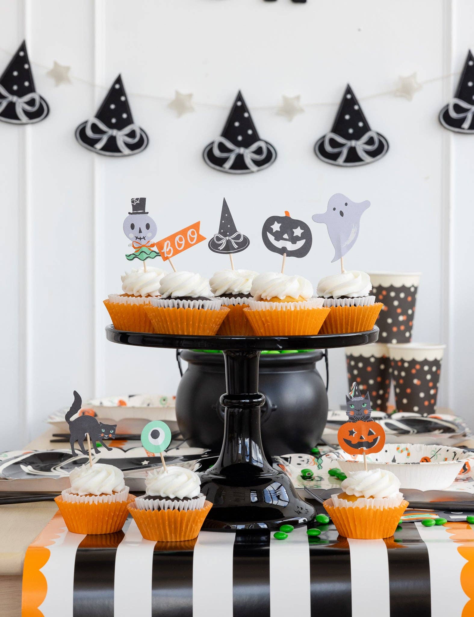 Halloween-themed cupcake display with decorative toppers on a black cake stand.