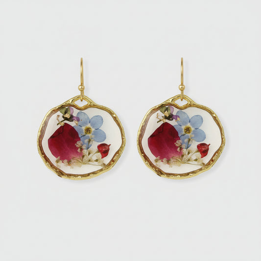Close-up of pink, red, blue, and purple flowers inside circular resin earrings