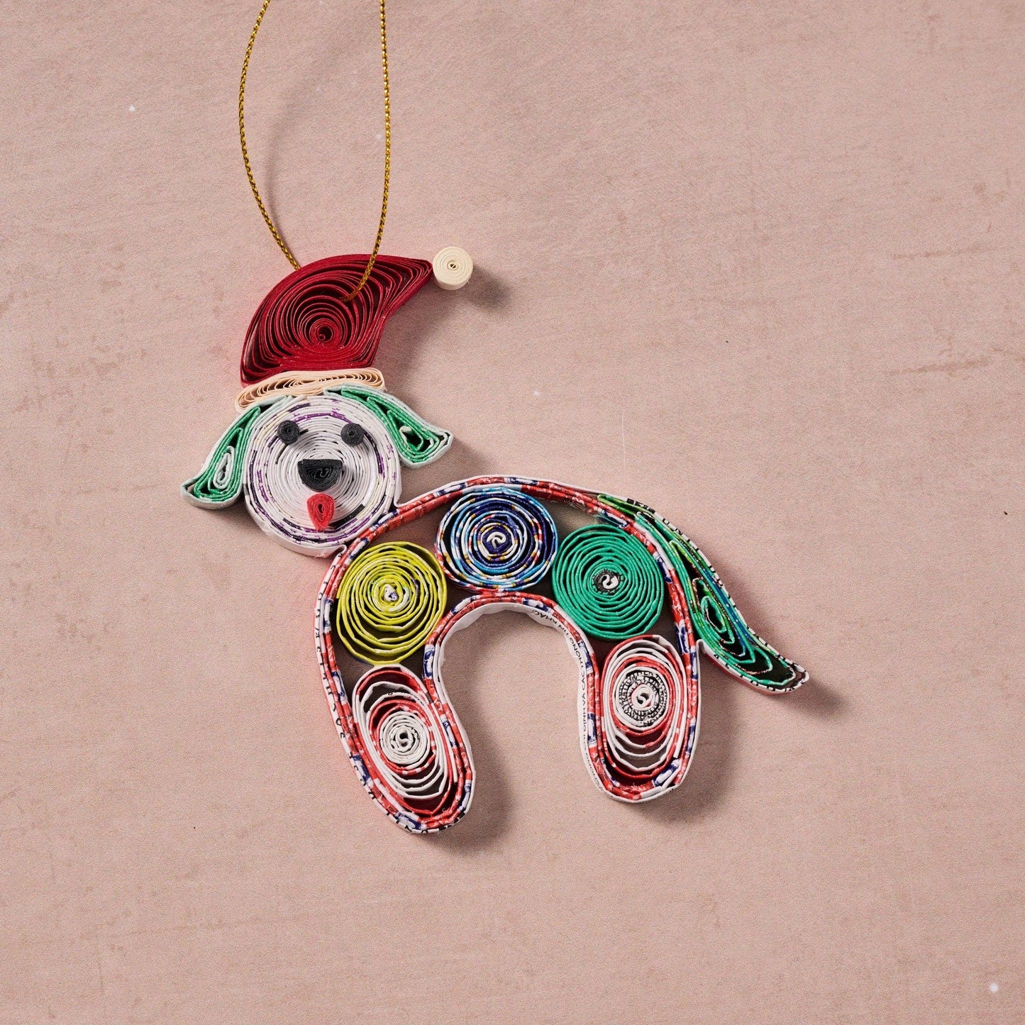 Colorful paper quilled dog ornament laid flat on a natural stone counter