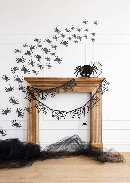 Glitter spiders crawling up a mantel and wall for Halloween party décor