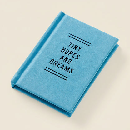 A mini blue journal titled 'Tiny Hopes and Dreams' on a light beige background