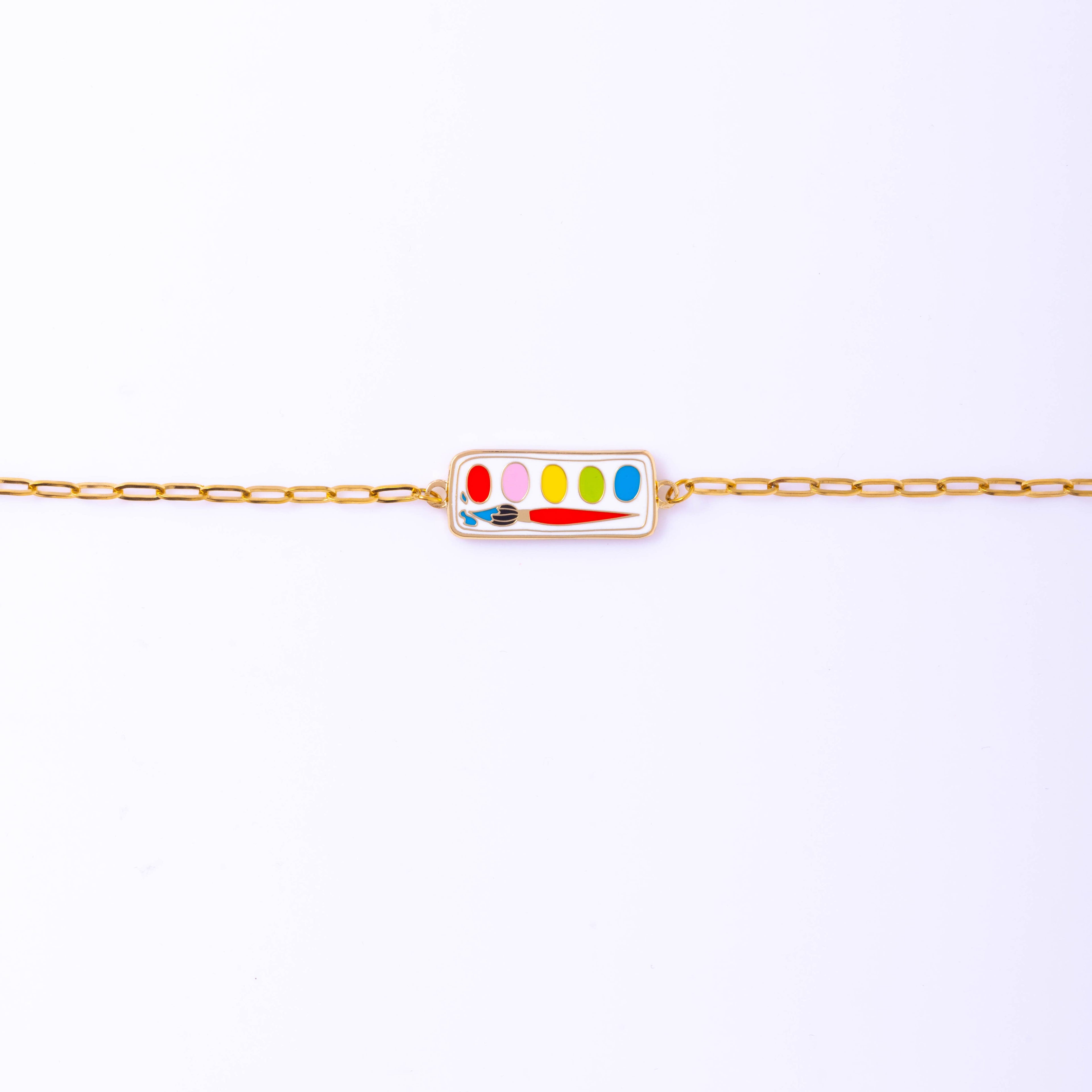 Delicate Paint Box Bracelet with a gold gilt enamel charm, presented in a matchbook-style box with a punch-hole for hanging.