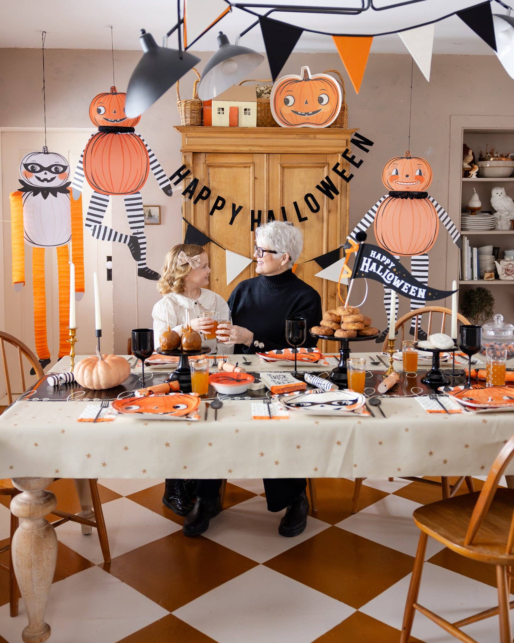 Tissue-limbed pumpkin Halloween character hanging from the ceiling in a decorated room