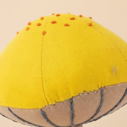 Yellow fabric mushroom figurine with brown stem on a white background