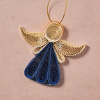 Decorative angel ornament with blue body and beige wings on a pink background