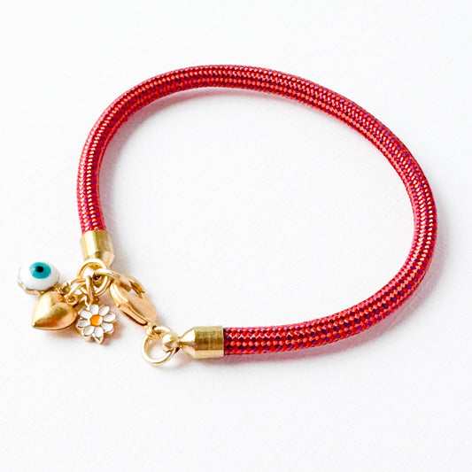 Red paracord charm bracelet with evil eye, daisy, and gold heart on white background