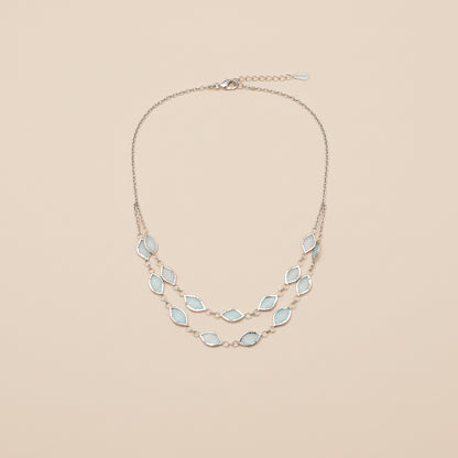 Necklace with light blue gemstones worn by a person against a neutral background