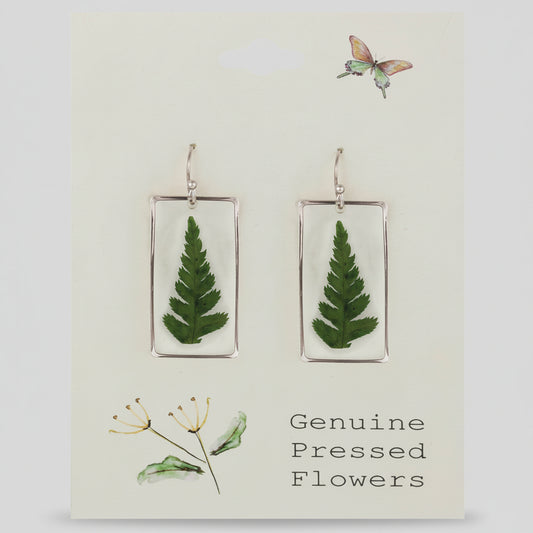 Earrings with pressed fern leaves on a card labeled 'Genuine Pressed Flowers'.