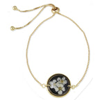 Gold bracelet with a black and white floral pendant on a white background
