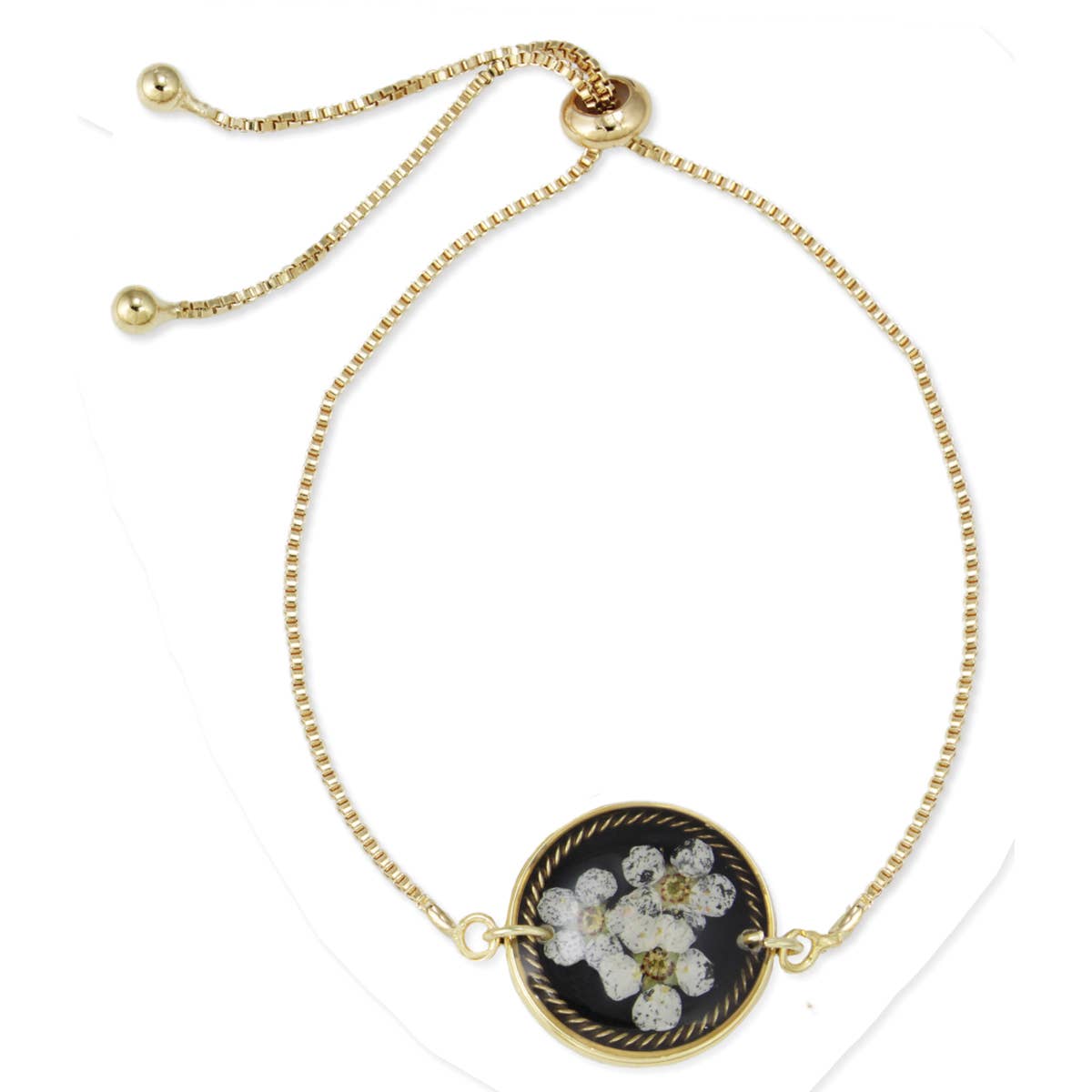 Gold bracelet with a black and white floral pendant on a white background