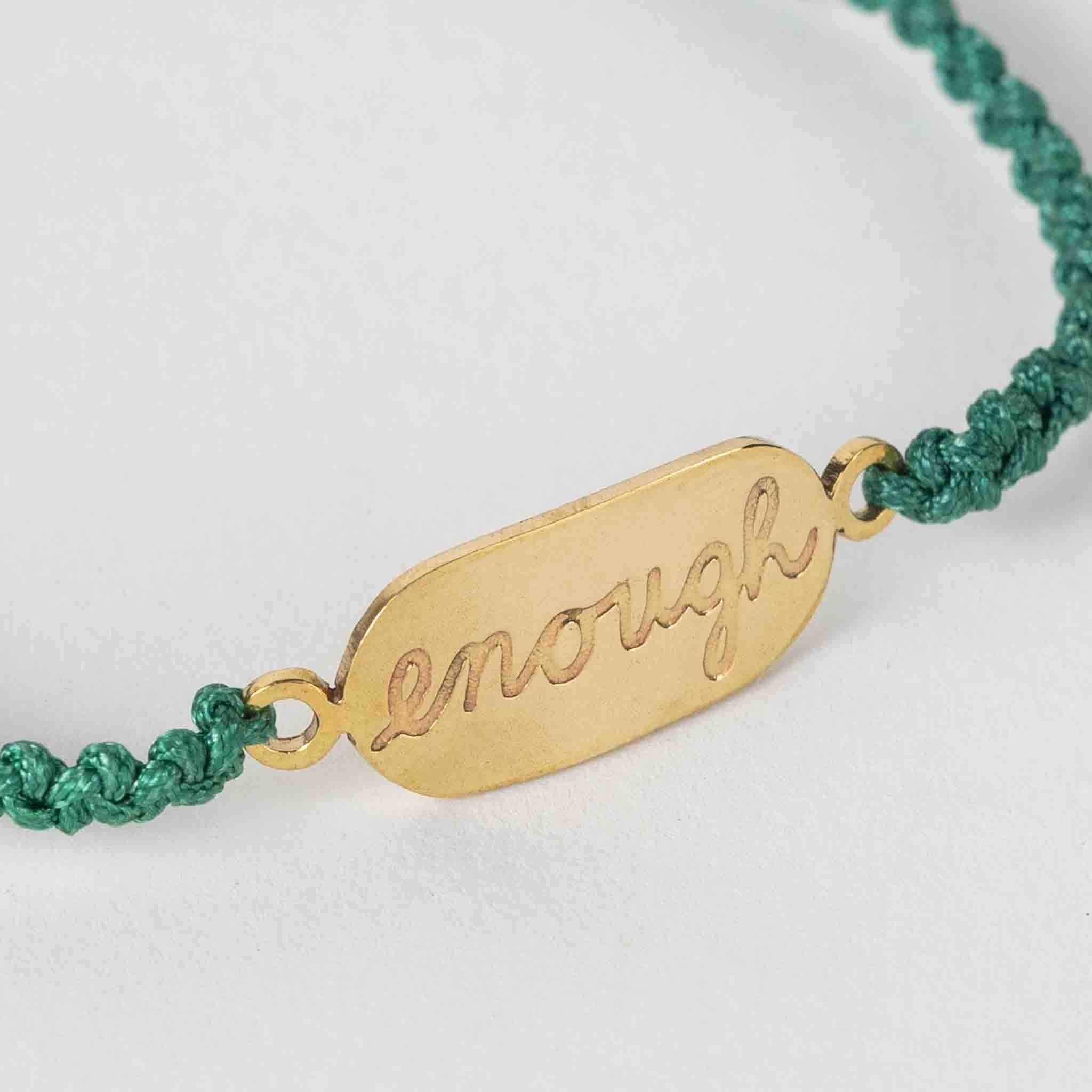 lose-up of artisan-made bracelet featuring bold brass affirmation on green nylon cord