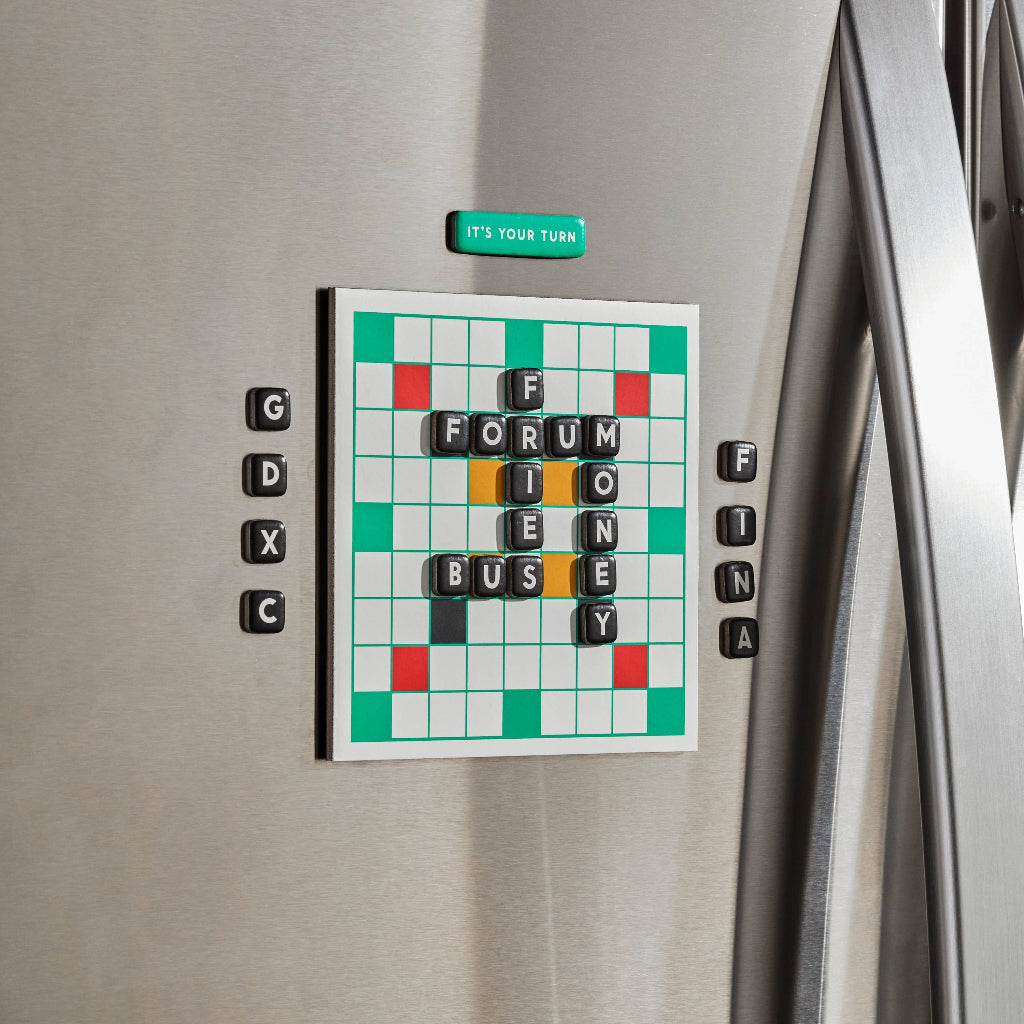Crossword puzzle magnetic board on a refrigerator with letters around it.
