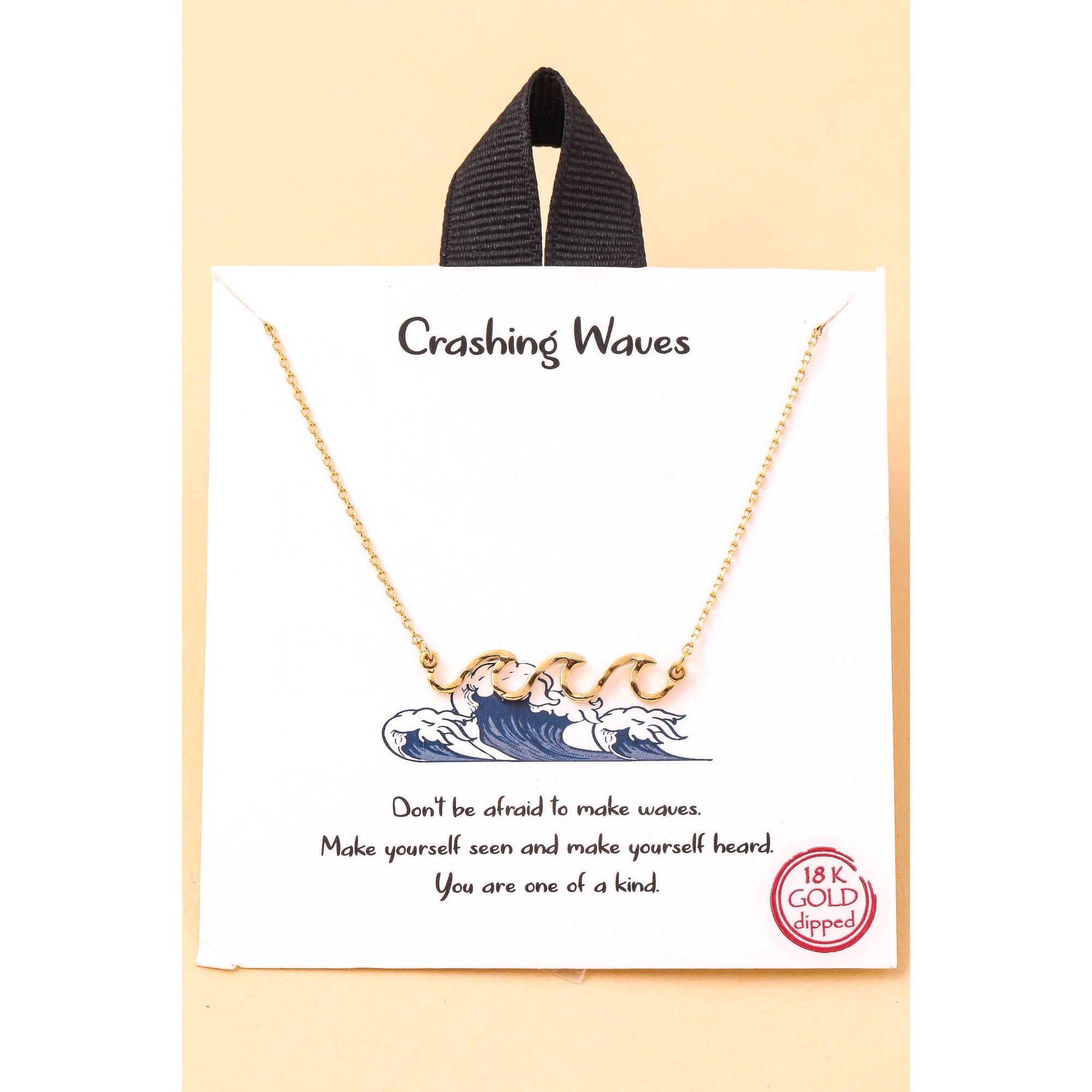 Close-up of crashing waves pendant on gold chain