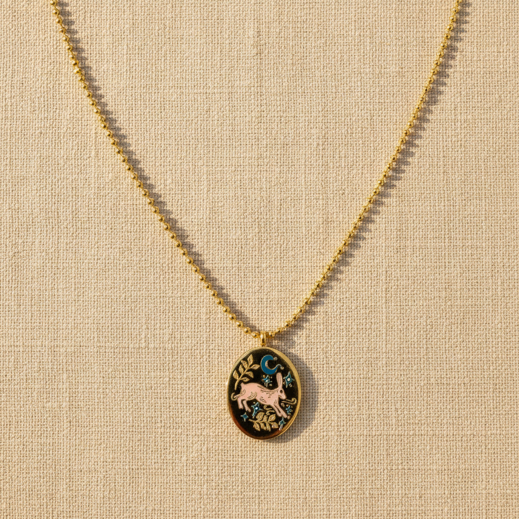 Gold necklace with a decorative pendant on a light beige background