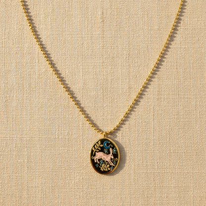 Gold necklace with a decorative pendant on a light beige background