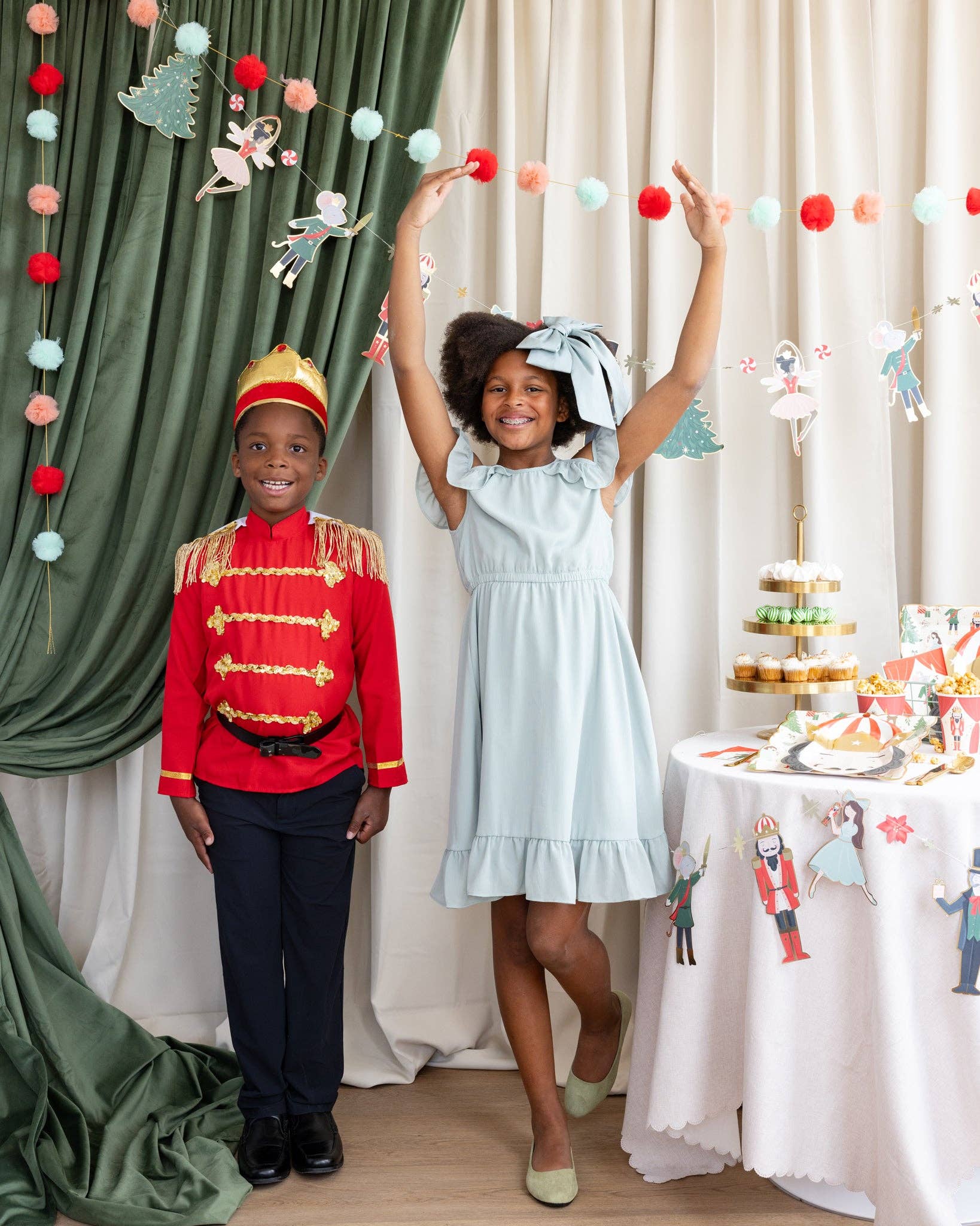 Two children in costumes standing in a decorated room with a table and festive decorations.