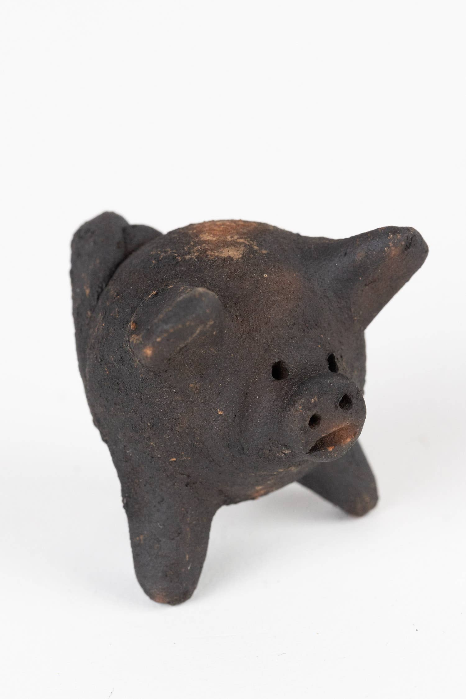 Small black pig-shaped ceramic figure on a white background