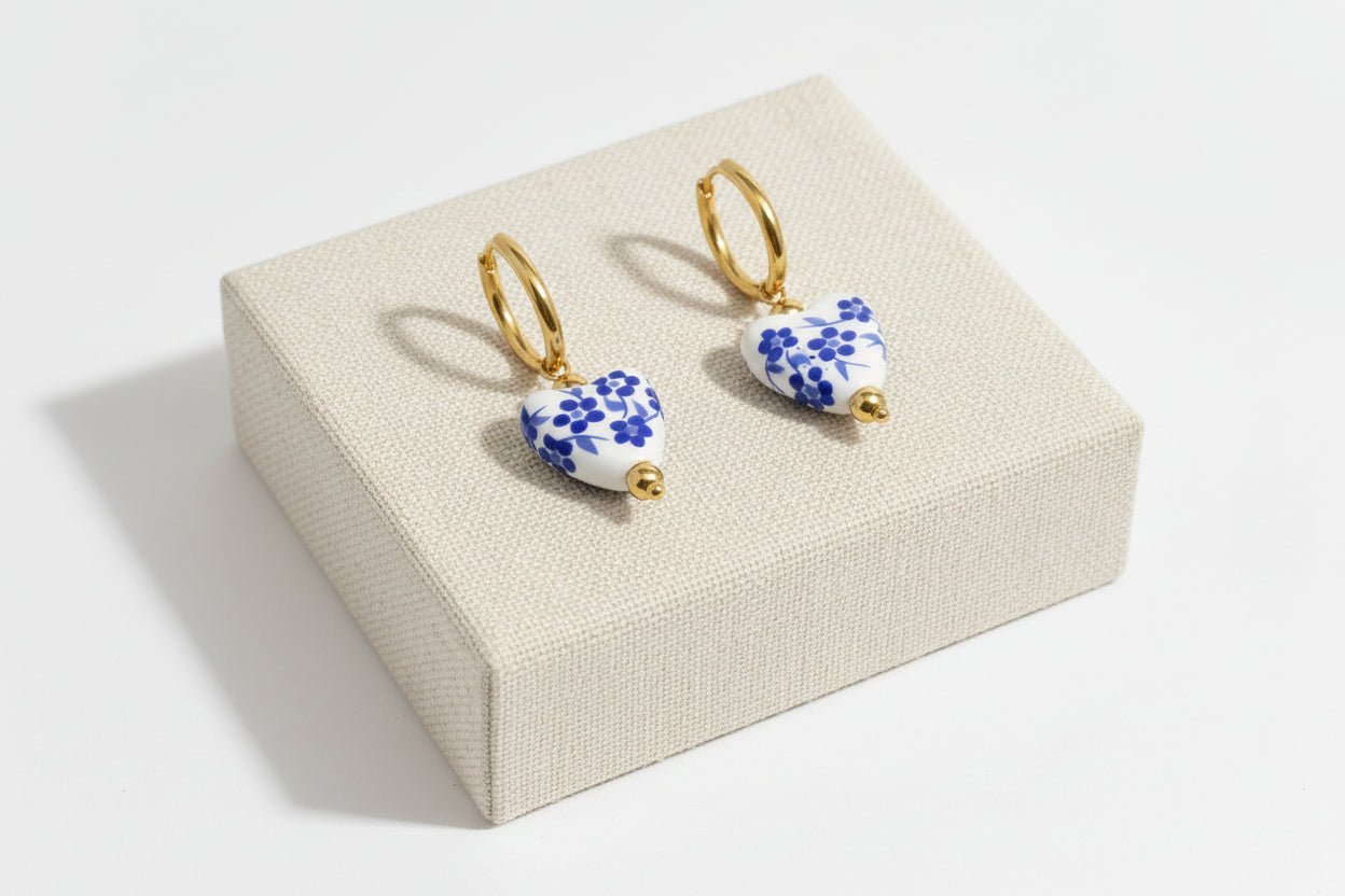 Pair of earrings with blue floral design on a beige jewelry box