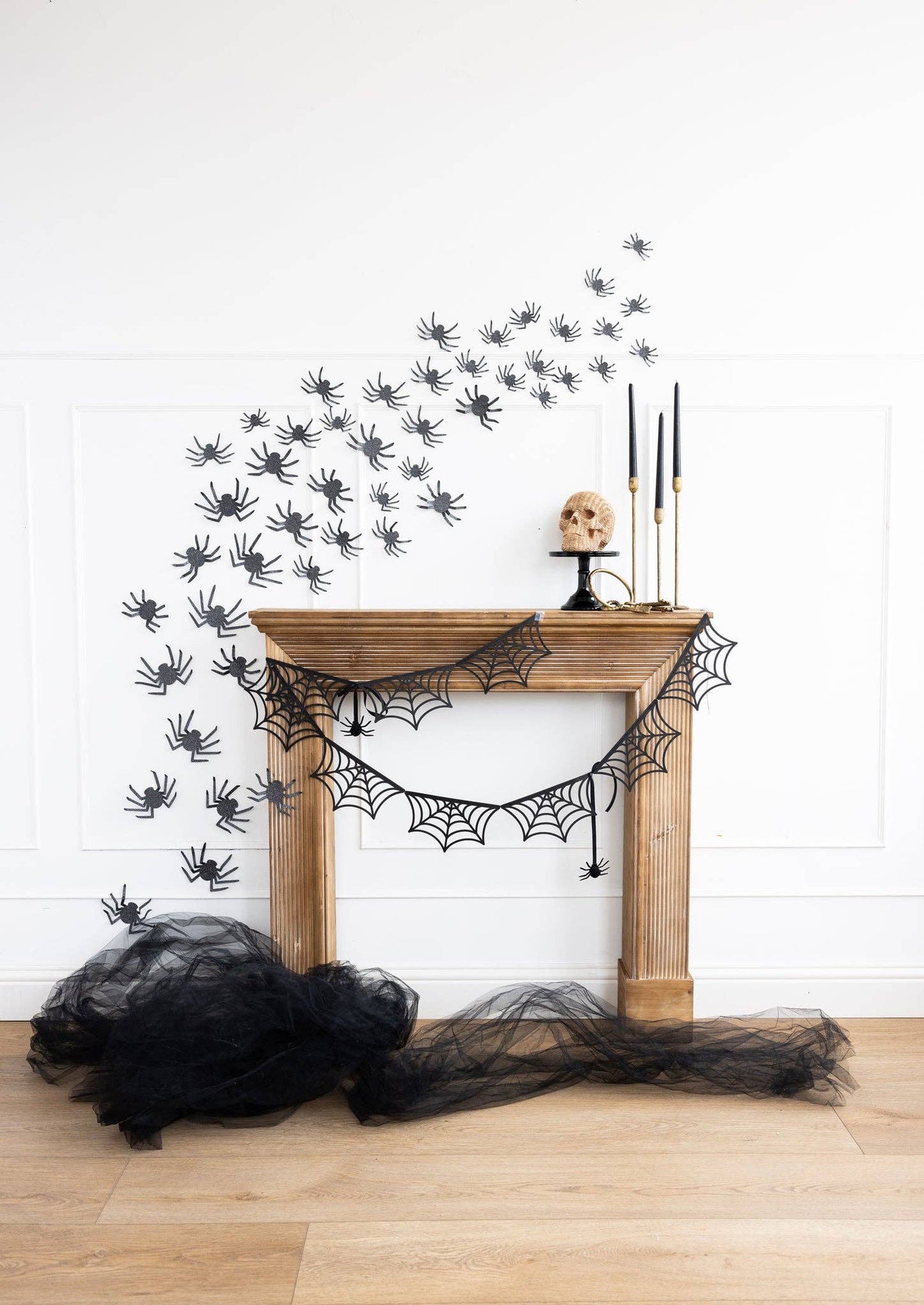 Halloween decorations including spider webs and black tulle on a fireplace.