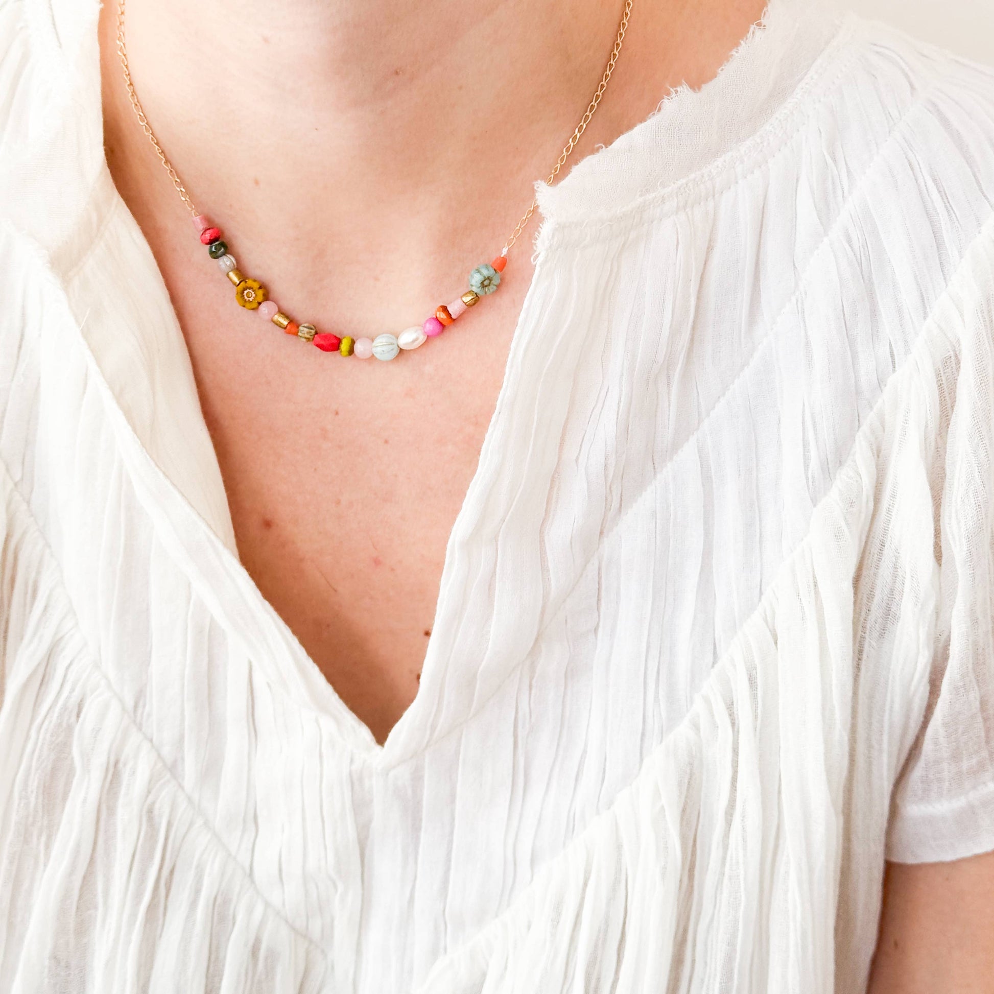 Blue and mustard flower necklace styled against white linen shirt