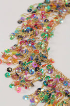 Multicolored sequin and gold metal ring beaded necklace on a white background