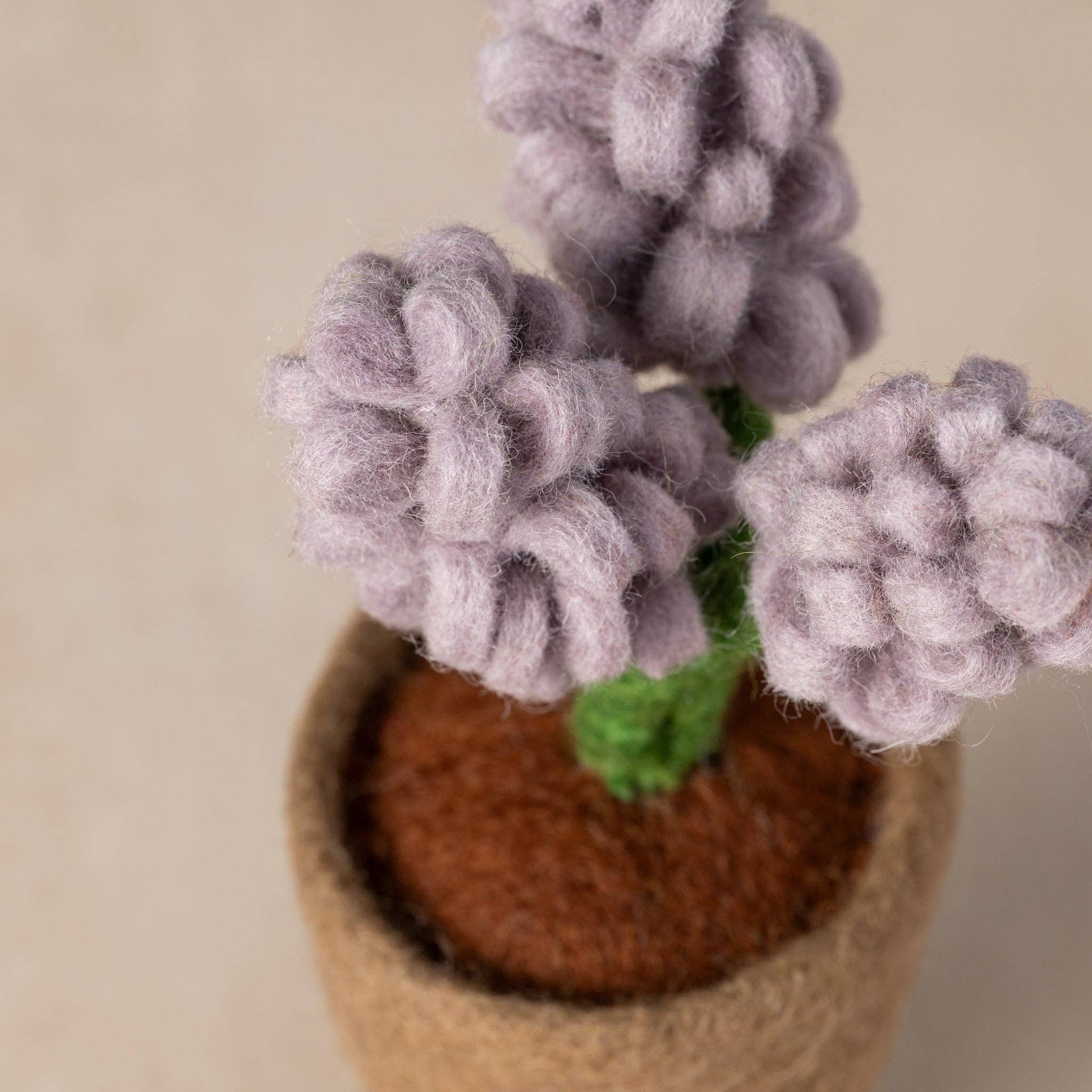 Close-up of handcrafted felt petals and green leaves in miniature wool planter