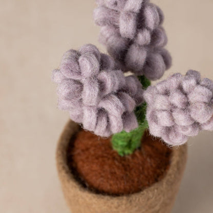 Close-up of handcrafted felt petals and green leaves in miniature wool planter