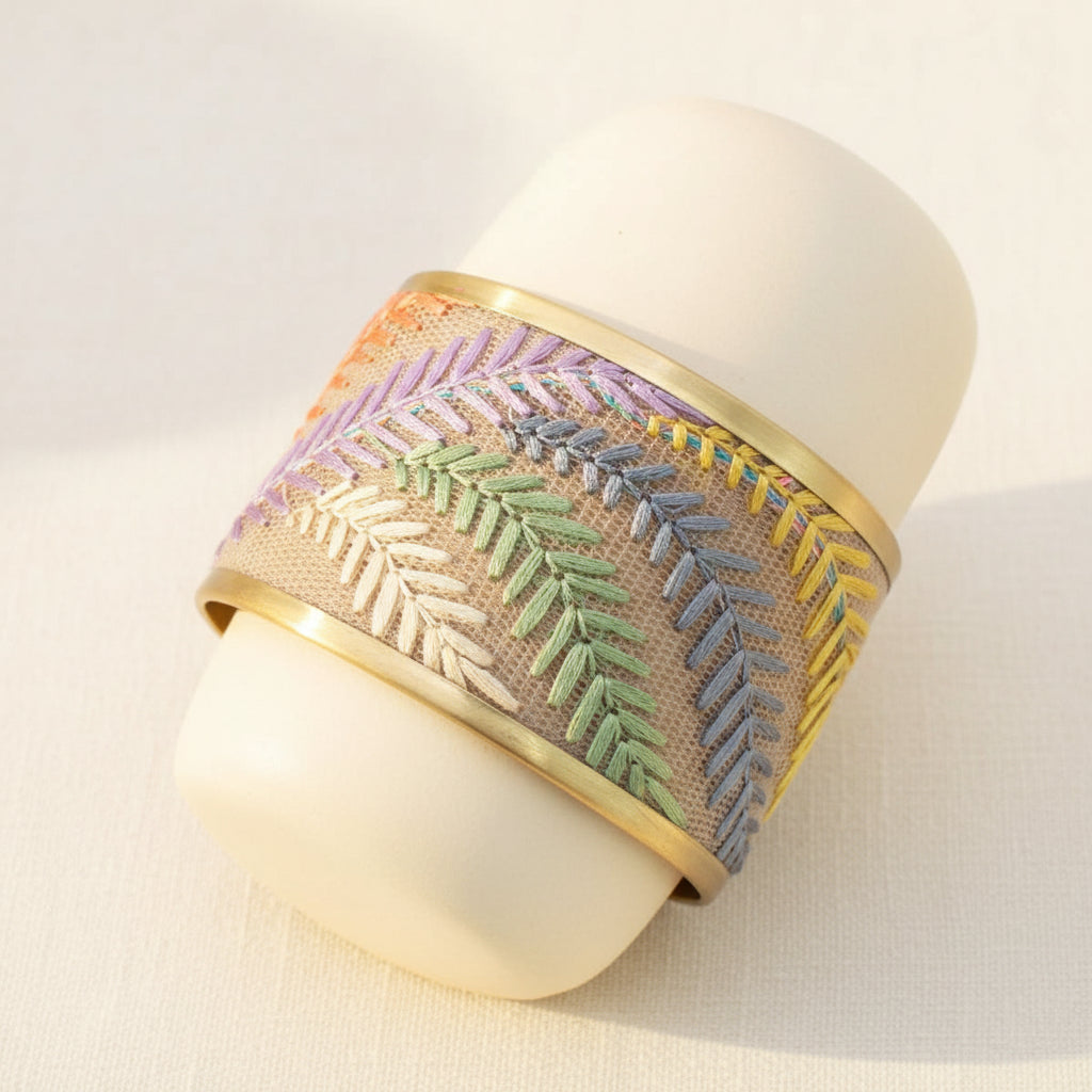 Decorative bracelet with embroidered pattern on a textured surface.
