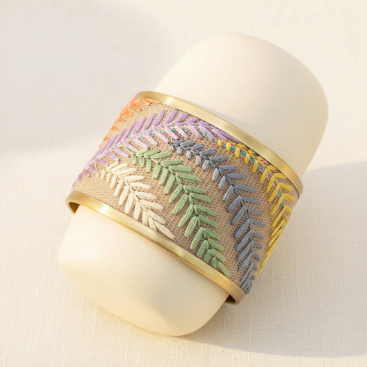 Decorative bracelet with embroidered pattern on a textured surface.