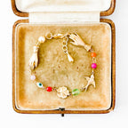 Adjustable gold charm bracelet with evil eye bead styled on neutral fabric
