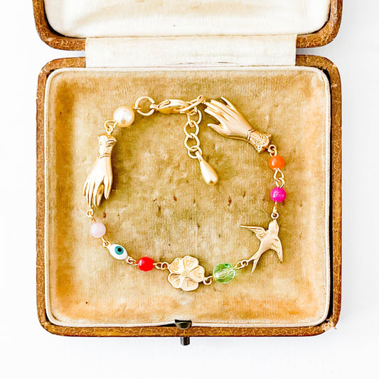 Adjustable gold charm bracelet with evil eye bead styled on neutral fabric