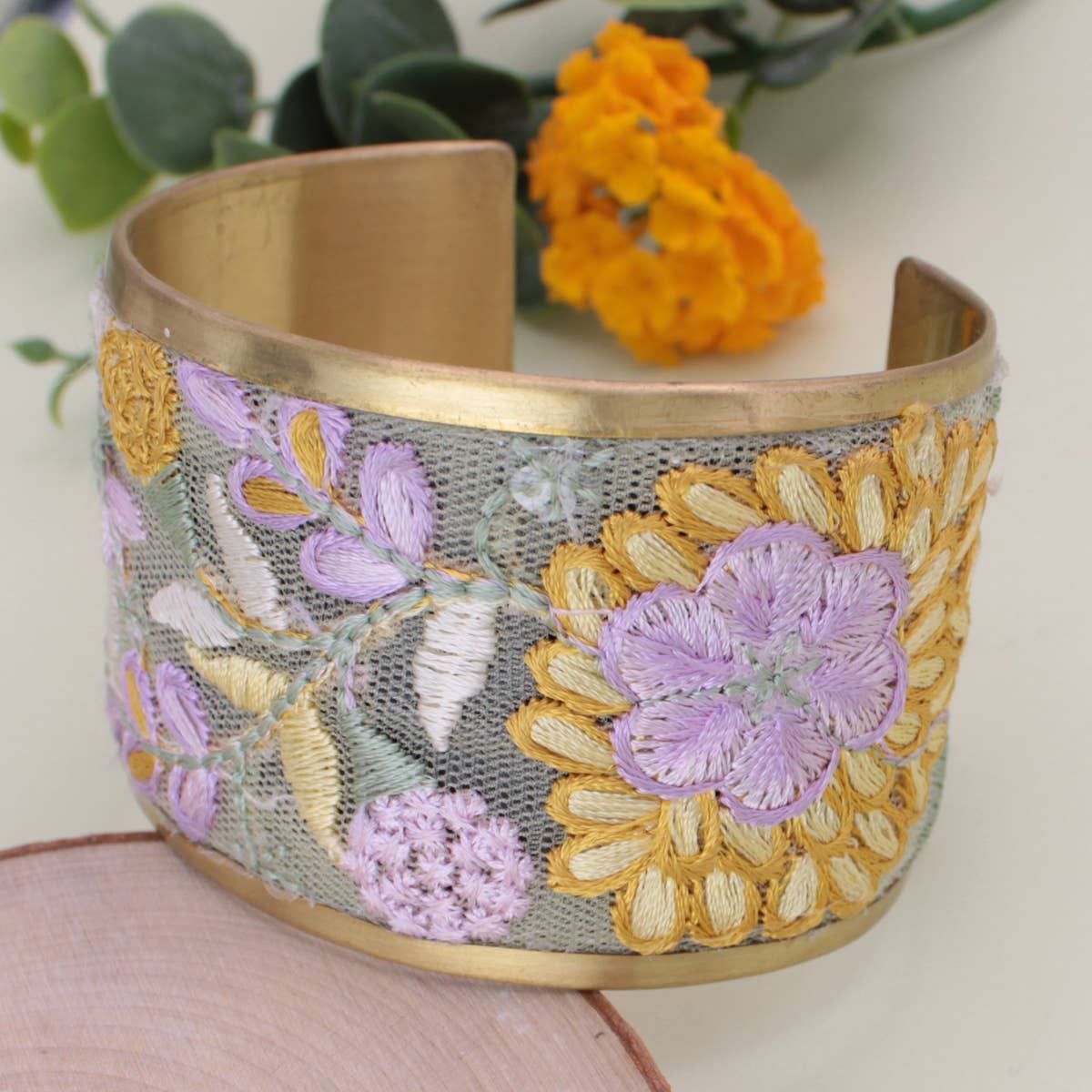 Gold bracelet with floral embroidery on a light background