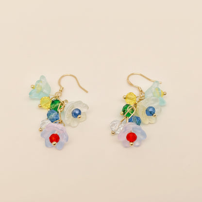 Colorful floral earrings with gold hooks on a light gray background