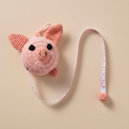 Crocheted pig measuring tape on a gray surface